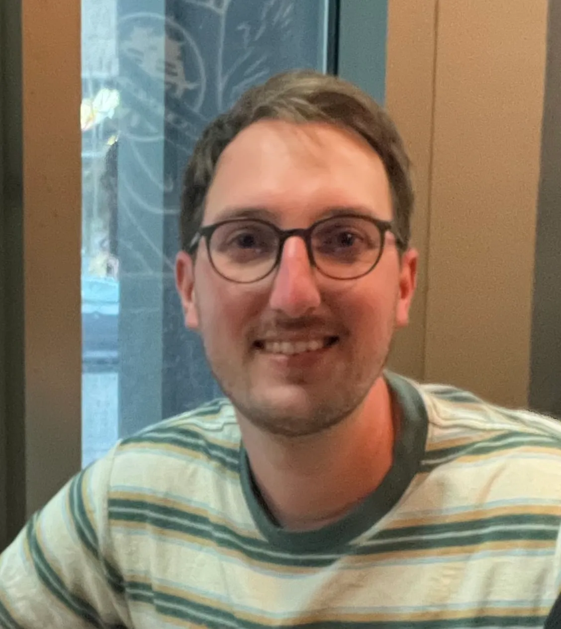 Smiling man wearing glasses and a striped sweater.